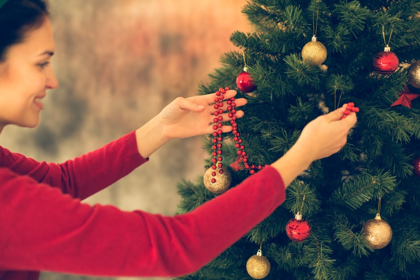 Frau schmückt den Weihnachtsbaum